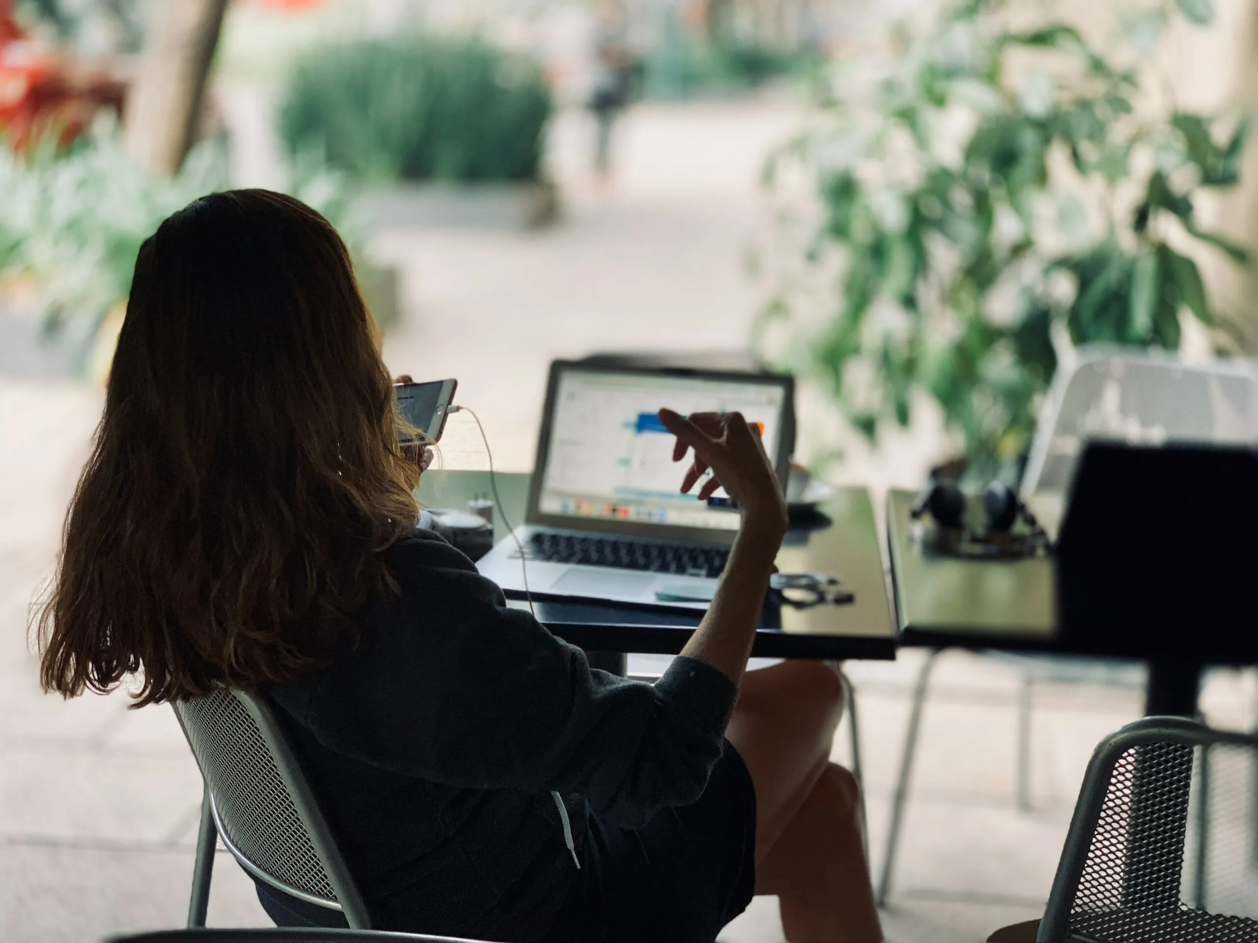 Kvinna som arbetar vid en laptop vid ett fönster med gröna växter