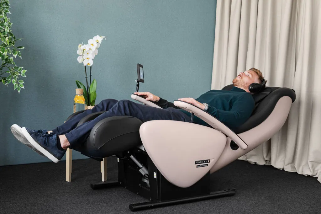 Person som vilar i en massagefåtölj i ett rum med blågrå vägg