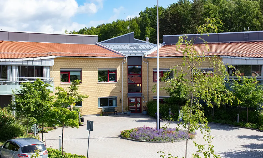 Omvårdnadsboende med gul fasad och grön gårdsplan