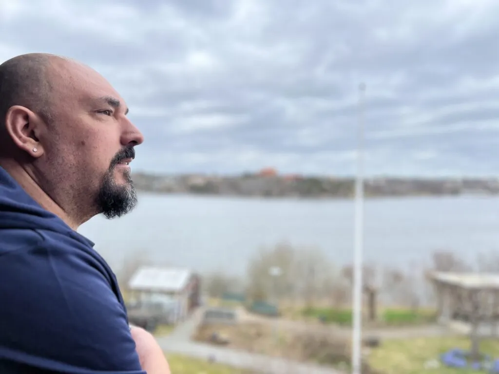 Man med skägg som tittar ut över en sjö