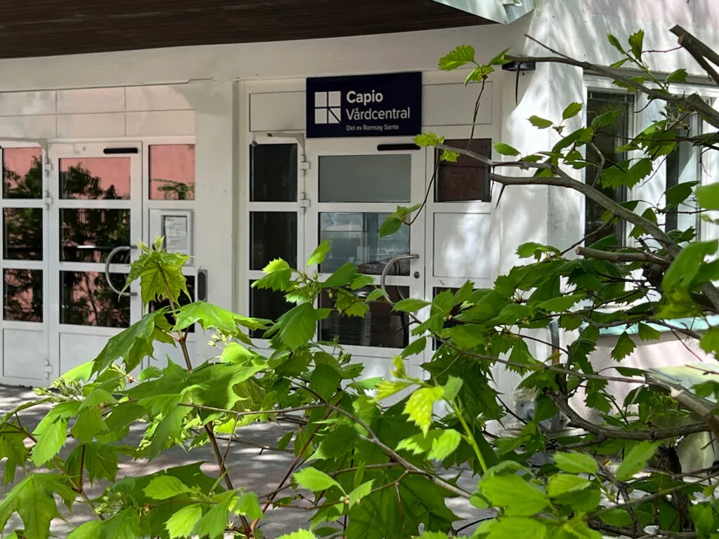 Entré med blommor och buskar framför ett vitt hus