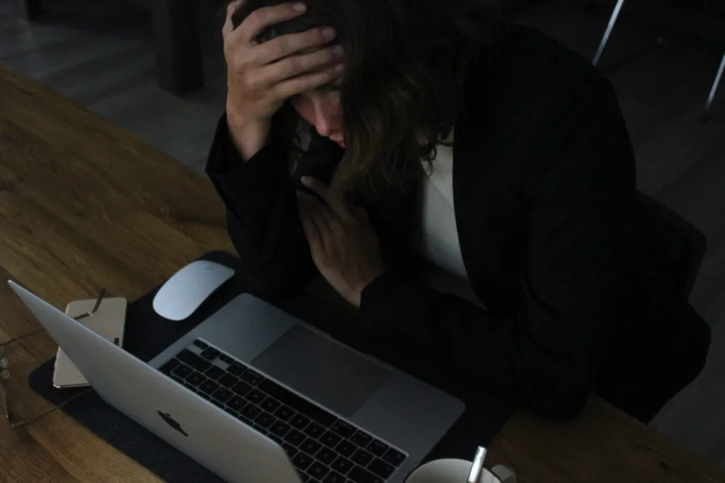 Person som håller handen mot pannan framför en laptop