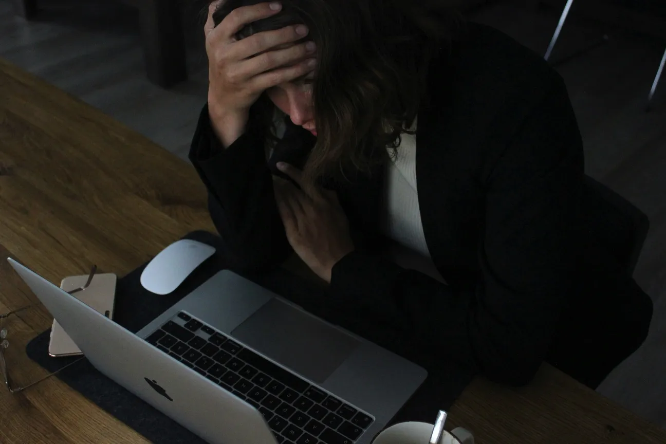 Person som håller handen mot pannan framför en laptop
