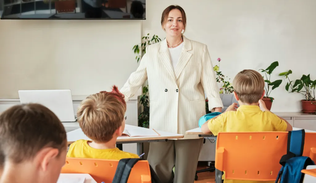 Lärare som står framför elever som sitter vid bänkar i ett klassrum
