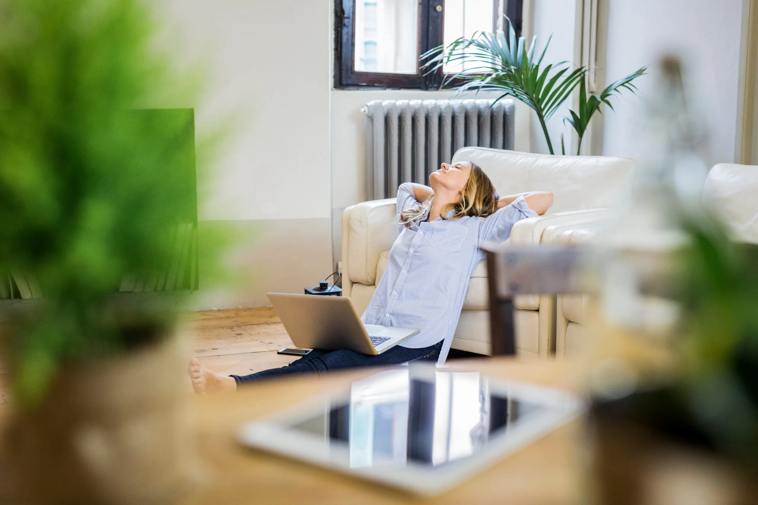 Kvinna som lutar sig bakåt i soffan med laptop i knät