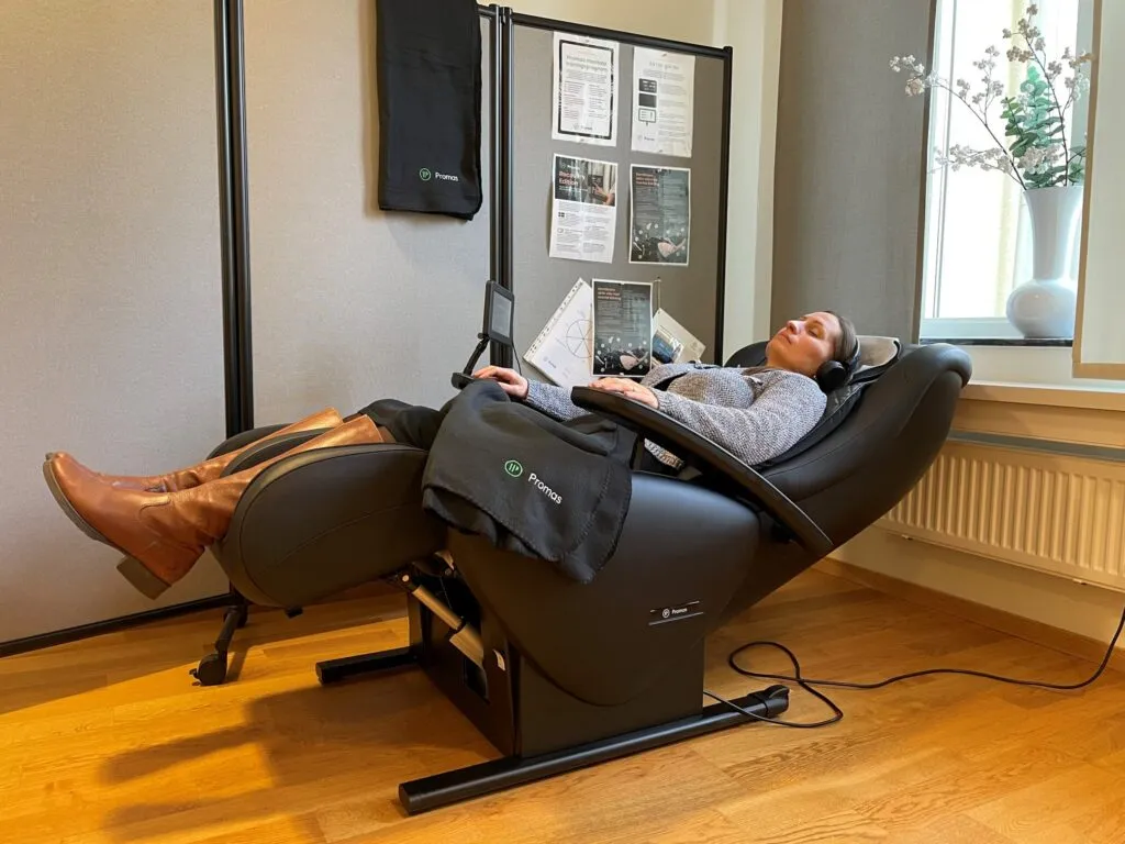 Person som vilar i en massagefåtölj i ett rum med trägolv