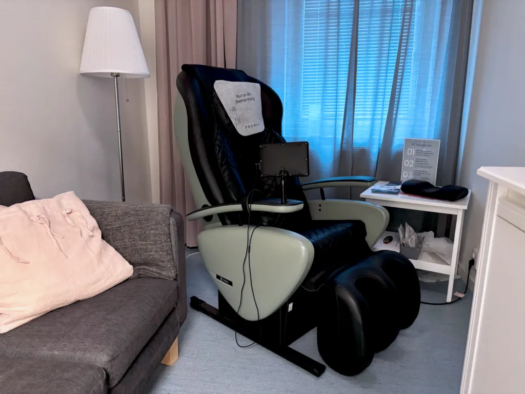 Återhämtningsfåtölj i ett vilrum på Smedjegården med soffa och blå gardiner