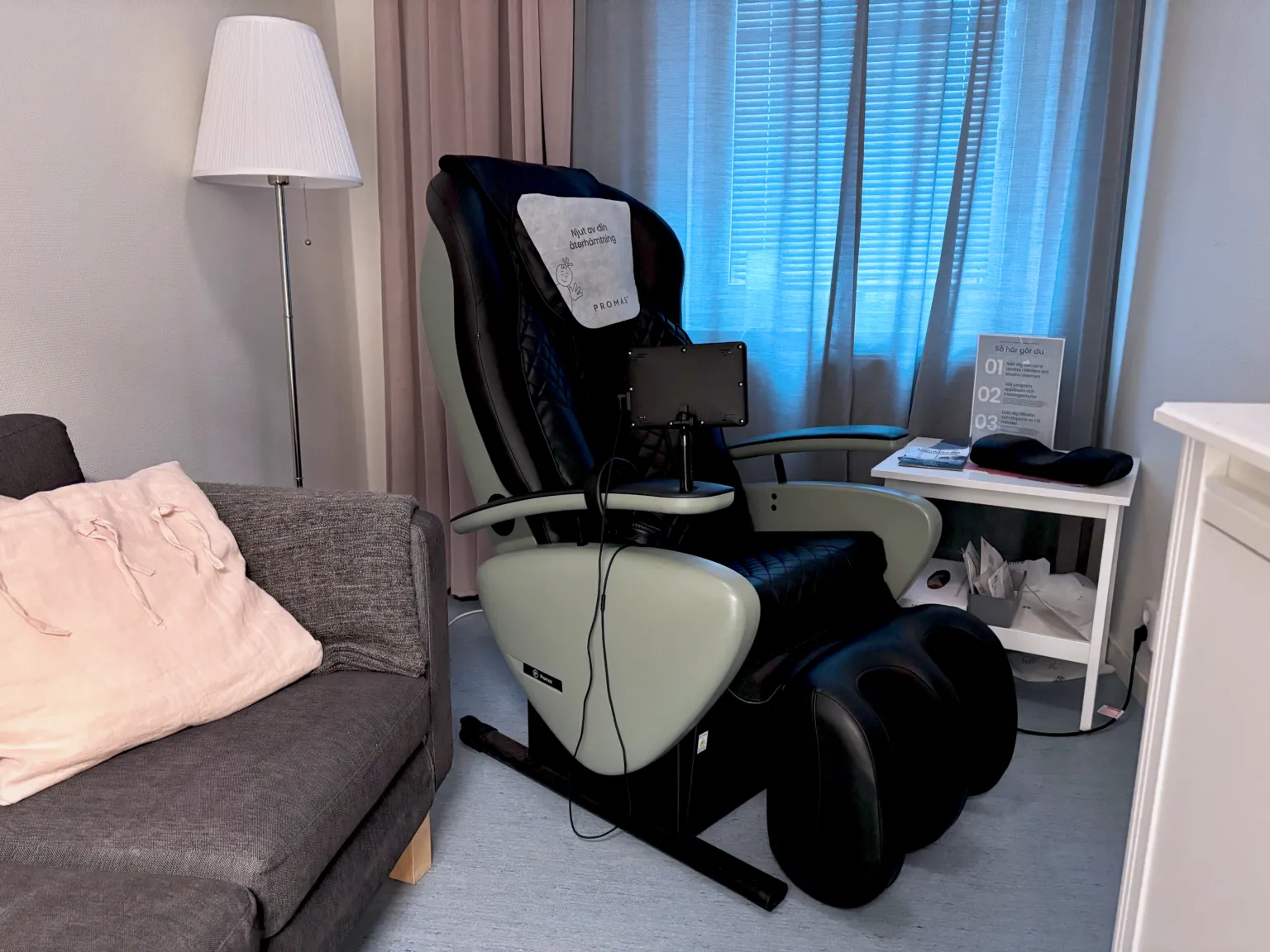 Återhämtningsfåtölj i ett vilrum på Smedjegården med soffa och blå gardiner